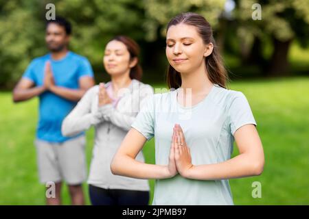 Eine Gruppe von Menschen, die im Sommerpark Yoga machen Stockfoto