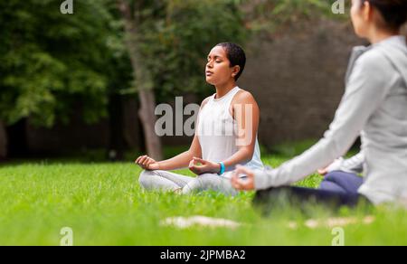 Eine Gruppe von Menschen, die im Sommerpark Yoga machen Stockfoto