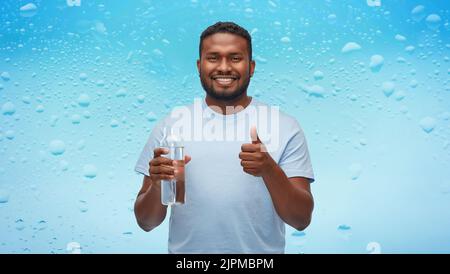 Glücklicher afrikanischer Mann mit Wasser in Glasflasche Stockfoto