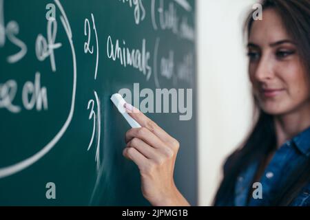Der Lehrer schreibt englische Regeln auf die Tafel. Sprache lernen. Stockfoto