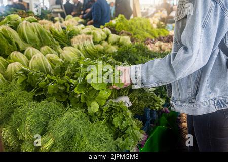 Kauf von frischen Bio-Produkten auf dem Bauernmarkt. Eine Frau wählt auf einem Lebensmittelmarkt frische Kräuter, Gemüse und Früchte Stockfoto