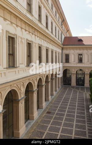 Innenhof des Czernin-Palastes (Černínský palác), in dem der Körper des Außenministers der Tschechoslowakei Jan Masaryk im Bezirk Hradčany in Prag, Tschechische Republik, gefunden wurde. Der Czernin-Palast diente als offizielle Residenz des Außenministers der Tschechoslowakei. Am 10. März 1948 wurde Jan Masaryk tot unter dem Fenster des Badezimmers seiner Wohnung aufgefunden. Wahrscheinlich beging er Selbstmord, indem er aus dem Fenster sprang oder wurde von den kommunistischen Behörden ermordet. Die schwarze Gedenktafel im Hintergrund markiert den Ort, an dem die Leiche gefunden wurde. Stockfoto