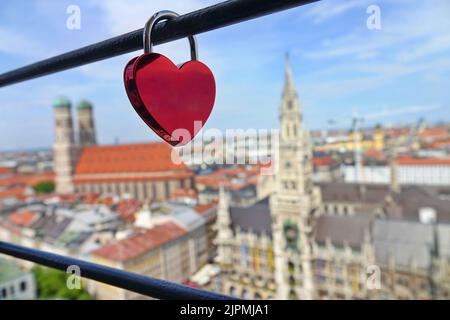 Ein herzförmiges Schloss und im Hintergrund Panoramablick auf die alte mittelalterliche gotische Architektur des Rathauses am Marienplatz. Quadratisch. München, Stockfoto