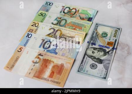 Die Banknoten im Wert von 100,50,20,10.5 weißrussischen Rubel und 100 Dollar auf dem grauen Hintergrund Stockfoto