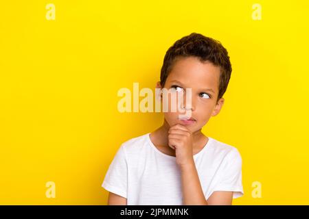 Foto von gesinnten kleinen Jungen Person suchen leeren Raum Arm berühren Gesicht Cosider Frage unsicher unsicher isoliert auf gelbem Hintergrund Stockfoto