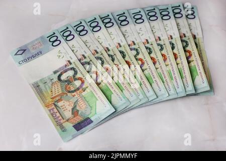 Ausgekleidete Banknoten von 100 weißrussischen Rubel auf grauem Hintergrund Stockfoto