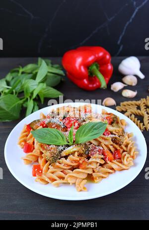 Eine Platte aus frisch gekochtem Vollkorn-Fusilli-Pasta in Tomatensauce auf dem Küchentisch Stockfoto