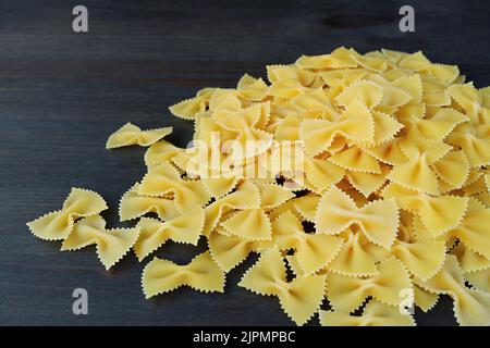 Stapel getrockneter Farfalle oder Bow-Tie Pasta auf schwarzem Holzhintergrund Stockfoto