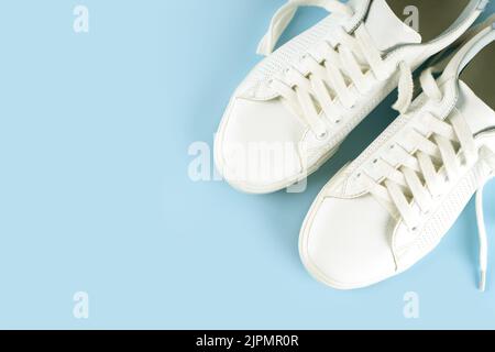 Paar weiße Sneakers auf blauem Hintergrund. Unisex-Schuhe, stylische weiße Sneaker. Draufsicht, flach liegend, Modell mit Platz für Text Stockfoto