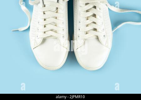 Paar weiße Sneakers auf blauem Hintergrund. Unisex-Schuhe, stylische weiße Sneaker. Draufsicht, flach liegend, Modell mit Platz für Text Stockfoto