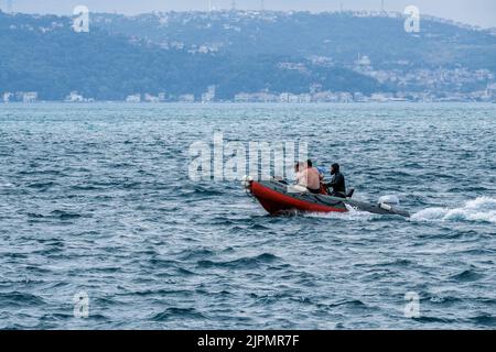 Harpunen-Fischer auf ihrem Boot in Bosporus gesehen. Während der Wind von Lodos im Bosporus weht, segeln und fischen Fischerboote. Wenn zu diesem Zeitpunkt internationale Schiffe den Bosporus passieren, kommt es zu starkem Verkehr. Stockfoto