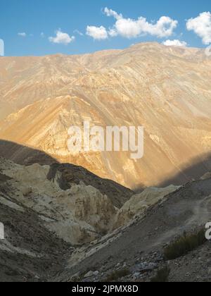 Blick über das Spiti-Tal mit hohen Bergrücken und steilen Hängen der Himalaya-Berge unter hellblauem Himmel mit Wolken im Sommer in der Nähe von Kaza, Indien. Stockfoto