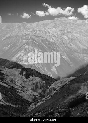 Blick über das Spiti-Tal mit hohen Bergrücken und steilen Hängen der Himalaya-Berge unter hellblauem Himmel mit Wolken im Sommer in der Nähe von Kaza, Indien. Stockfoto