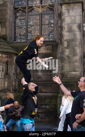 Edinburgh, Schottland, Großbritannien, 19.. August 2022. Fringe Performer auf der Royal Mile: Die Straße ist voll von Fringe-Besucher, Straßenkünstler und Darsteller von Shows, die an einem sonnigen Tag Flugblätter verteilen. Im Bild: Akrobaten aus Boom! Kredit: Sally Anderson/Alamy Live Nachrichten Stockfoto