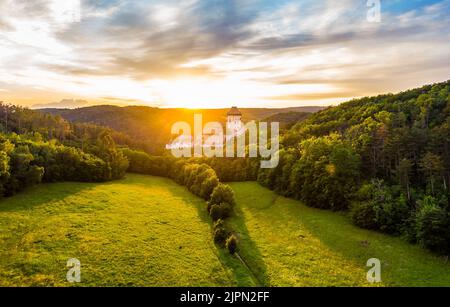 Luftaufnahme des wunderschönen Sonnenuntergangs über dem Schloss Karlstejn, Tschechische Republik. Drohne Aufnahme von alten Schloss mit in der Nähe von Wald. Burg im gotischen Stil war b Stockfoto