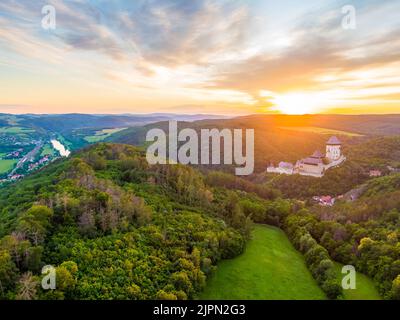 Luftaufnahme des wunderschönen Sonnenuntergangs über dem Schloss Karlstejn, Tschechische Republik. Drohne Aufnahme von alten Schloss mit in der Nähe von Wald. Burg im gotischen Stil war b Stockfoto