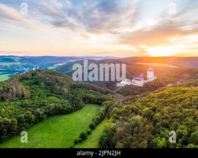 Luftaufnahme des wunderschönen Sonnenuntergangs über dem Schloss Karlstejn, Tschechische Republik. Drohne Aufnahme von alten Schloss mit in der Nähe von Wald. Burg im gotischen Stil war b Stockfoto