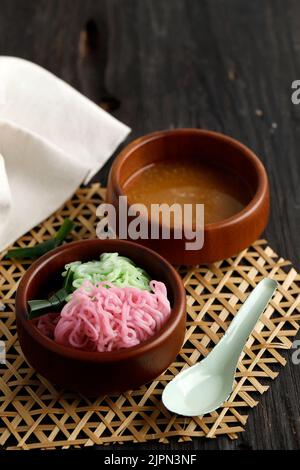 Petulo oder Putu Mayang ist ein traditioneller indonesischer Snack aus Reismehl, der mit Kokosmilch und Palmzucker-Sauce serviert wird Stockfoto