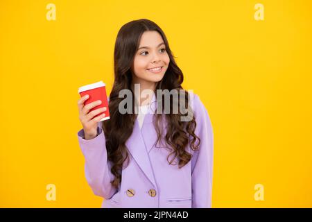 Kind mit Kaffee- oder Teetasse isoliert auf gelbem Studiohintergrund. Teenager-Mädchen mit Getränk zum Mitnehmen. Glückliches Gesicht, positive und lächelnde Emotionen Stockfoto