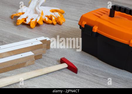 Werkzeugkiste und Spanplatten auf Holzboden , Hammer. Stockfoto