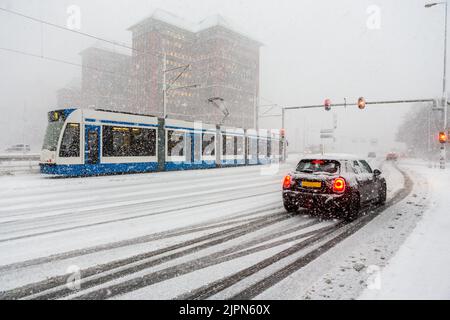 Auto wartet auf Ampeln an der Kreuzung Cornelis Lelylaan und Einsteinweg in Amsterdam während eines starken Schneesturms in den Niederlanden. Stockfoto