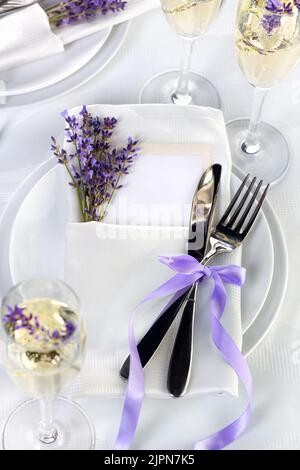 Esstisch im provenzalischen Stil, mit Lavendel Champagner, gefaltete Serviette mit Besteck, dekoriert mit frischem Lavendel. Detail des Hochzeitsessens. Mittwoch Stockfoto