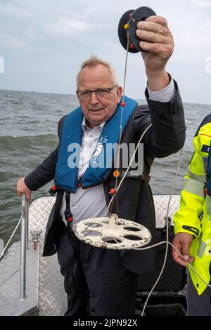 19. August 2022, Mecklenburg-Vorpommern, Ueckermünde: Till Backhaus (SPD), Landesumweltminister von Mecklenburg-Vorpommern, steht im Hafen von Ueckermünde an der Stettin-Lagune mit einer Schwimmweste und einer Secchi-Scheibe zur Sichtbarkeitsmessung. Mitarbeiter des Landesamtes für Landwirtschaft und Umwelt Vorpommerns (StALU VP) haben weitere Wasserproben entnommen. Im deutschen Teil der Lagune wurden bisher nach offiziellen Angaben keine Fischkadaver im Zusammenhang mit dem oder-Fischabtötung entdeckt. Dennoch, als Vorsichtsmaßnahme, autoritäre Stockfoto