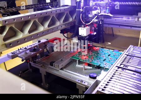 Errichter von SMD-Teilen auf Leiterplatten und Lötteilen. Maschine für die automatische Montage und das Löten von elektronischen Leiterplatten. Elektrisches Löten Stockfoto