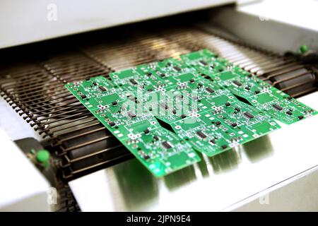 PCB-Trocknungstechnologie. Das fertige Brett verlässt den Trockenofen entlang des Förderers. Stockfoto