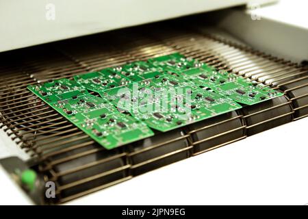 PCB-Trocknungstechnologie. Das fertige Brett verlässt den Trockenofen entlang des Förderers. Stockfoto