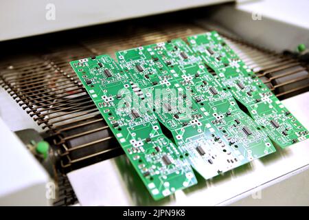 PCB-Trocknungstechnologie. Das fertige Brett verlässt den Trockenofen entlang des Förderers. Stockfoto