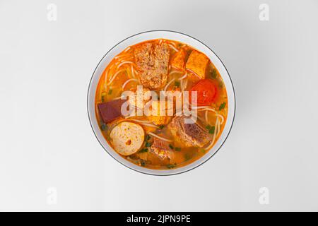 Bun Rieu Cua, Krabbenpaste Vermicelli-Suppe mit gehackten Garnelen, Tofu, Tomaten, Garnelenpaste, vietnamesisches Essen isoliert auf weißem Hintergrund, Draufsicht Stockfoto