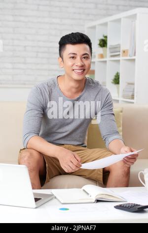 Hübscher junger Unternehmer, der zu Hause mit Dokumenten arbeitet Stockfoto