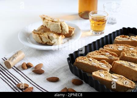 Cantucci, italienische Mandelkekse auf einem Tablett. Süßer Wein namens Vin Santo auf dem Hintergrund. Nahaufnahme. Stockfoto