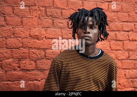 Junger, hübscher, eleganter schwarzer Mann mit natürlichen Haardreadlocks. Afroamerican guy.stairs, Wand bemalt mit Graffiti in armen Viertel der Street Art Kultur Stockfoto