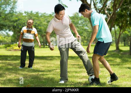 Vietnamesische Familie spielt Fußball im lokalen Park Stockfoto