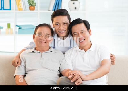 Lächelnder Teenager umarmte seinen Vater und Großvater Stockfoto