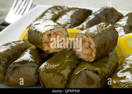 Ganze und halbierte griechische Dolmades auf einem Teller aus der Nähe Stockfoto