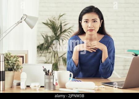 Porträt einer jungen asiatischen Unternehmerin an ihrem Tisch im Büro Stockfoto