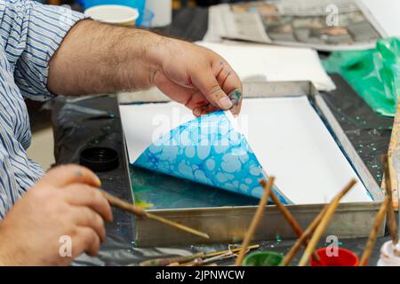 Der Künstler Tugay Yalcin unterrichtet Anfänger in der Fenham Library, Newcastle upon Tyne, Großbritannien, die Kunst des Papiermarbling, einer türkischen Disziplin, die als ebru bekannt ist. Stockfoto