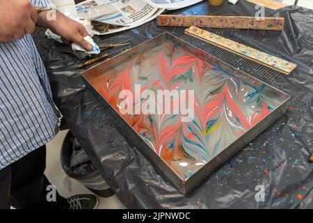 Der Künstler Tugay Yalcin unterrichtet Anfänger in der Fenham Library, Newcastle upon Tyne, Großbritannien, die Kunst des Papiermarbling, einer türkischen Disziplin, die als ebru bekannt ist. Stockfoto