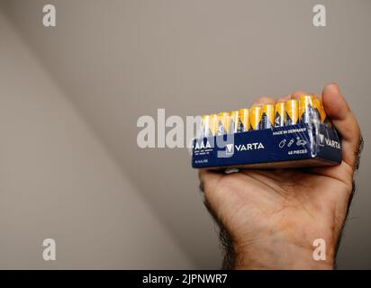 Paris, Frankreich - 1. Aug 2022: POV männliche Handpackung mit neuen Varta AAA 40 Stück Made in Germany Alkaline Batterien Stockfoto