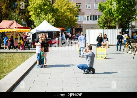 Straßburg, Frankreich - 12. Sep 2015: Junger Mann fotografiert seinen Bruder mit Frau und Kindern vor dem Brunnen am zentralen Place Kleber Stockfoto