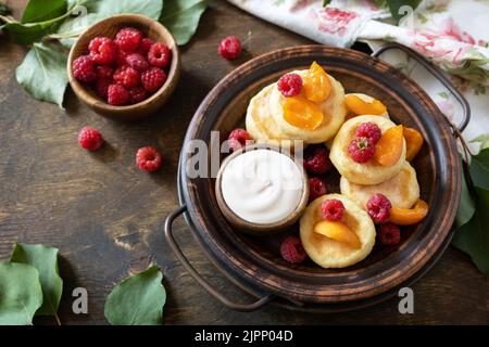 Gesundes und leckeres Frühstück am Morgen. Hausgemachte Hüttenkäse Pfannkuchen glutenfrei (Syrniki, Quark Fritters) mit Beeren auf Holz rustikalen Backgroun Stockfoto