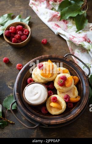 Gesundes und leckeres Frühstück am Morgen. Hausgemachte Hüttenkäse Pfannkuchen glutenfrei (Syrniki, Quark Fritters) mit Beeren auf Holz rustikalen Backgroun Stockfoto