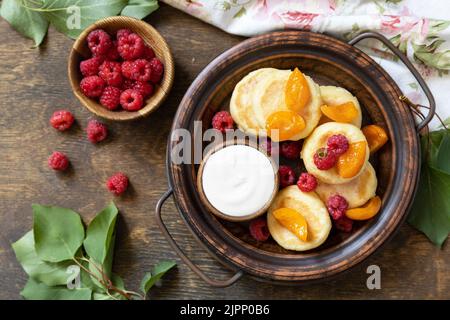 Gesundes und leckeres Frühstück am Morgen. Hausgemachte Hüttenkäse Pfannkuchen glutenfrei (Syrniki, Quark Fritters) mit Beeren auf Holz rustikalen Backgroun Stockfoto