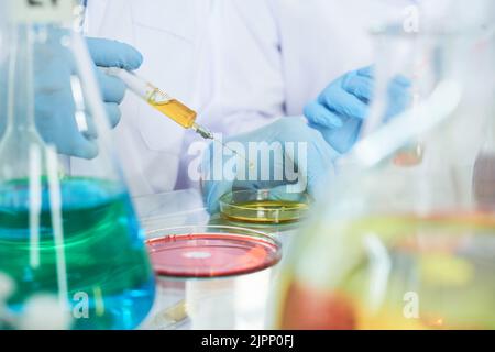 Nahaufnahme eines talentierten Wissenschaftlerteams mit Gummihandschuhen und weißen Mänteln, das an der Entwicklung eines brandneuen Krebsimpfstoffs im modernen Labor arbeitet Stockfoto