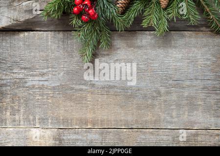 Postkartenmotiv im Vintage-Stil. Rote Weihnachtsdekorationen auf einem Holzhintergrund. Stockfoto
