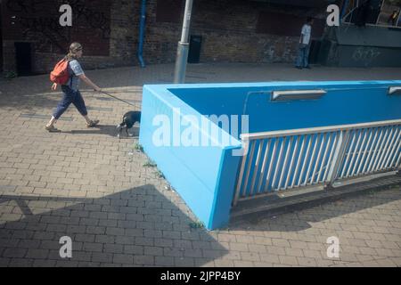 Eine Frau geht mit ihrem Hund am 18.. August 2022 in London, England, an der Rampe einer Unterführung bei Waterloo an der Southbank vorbei. Stockfoto