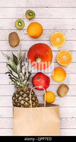 Umweltfreundliche Einkaufstasche mit egxotischen Früchten auf Holzhintergrund. Flat Lay Sommer Food Konzept Stockfoto